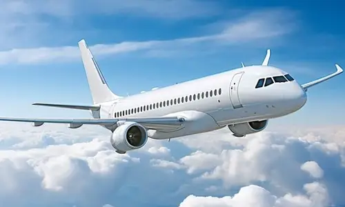 Commercial passenger airplane flying above the clouds under a clear blue sky, representing airport transportation and taxi services.